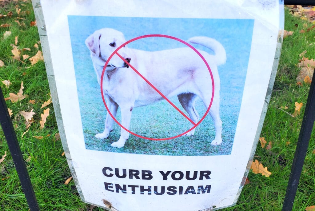 an anti-dog-poop sign features a crossed out dog with text that reads "curb your enthusiasm"