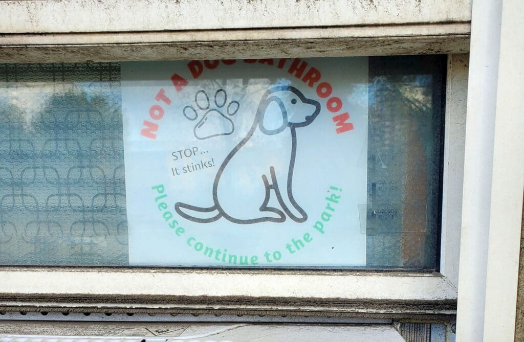 an anti-dog-poop sign located on a floor-level apartment window compels dog owners not to leave their dog's poop outside the residents' window